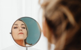 A woman looks at her reflection in a mirror