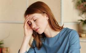 An exhausted lady sits at a table with her head in her hands