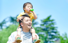 A child sits on their father's shoulders
