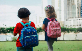 Two children walk across some grass